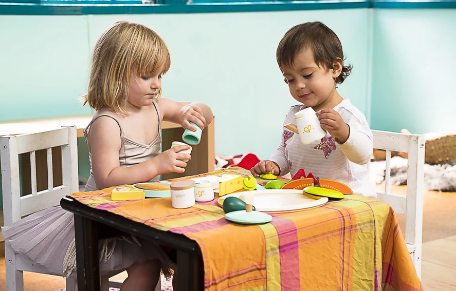 Two children at a small table sharing a game of play food