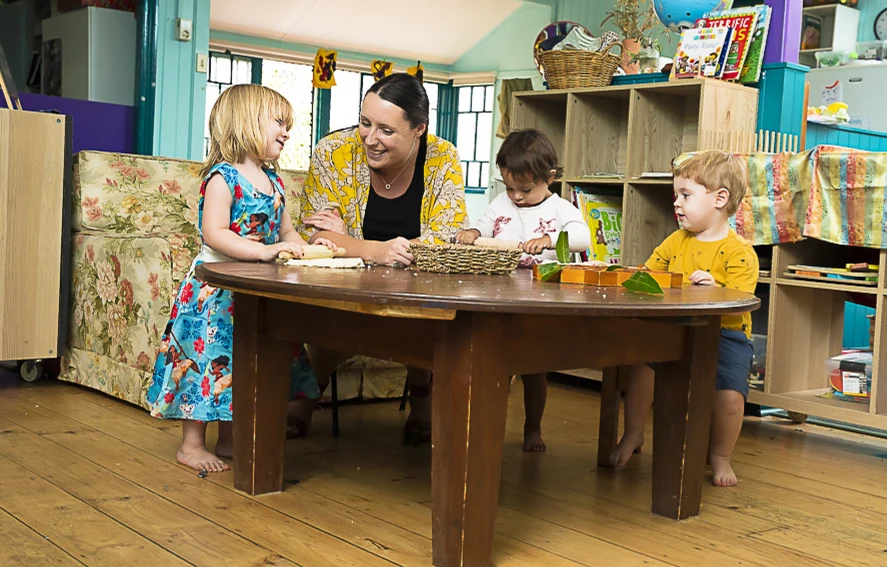 An educator talking with a group of children seated around a wooden table