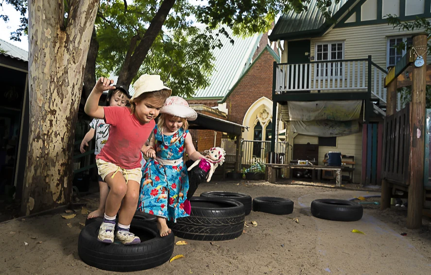 Two children balancing together on a tyre, holding hands
