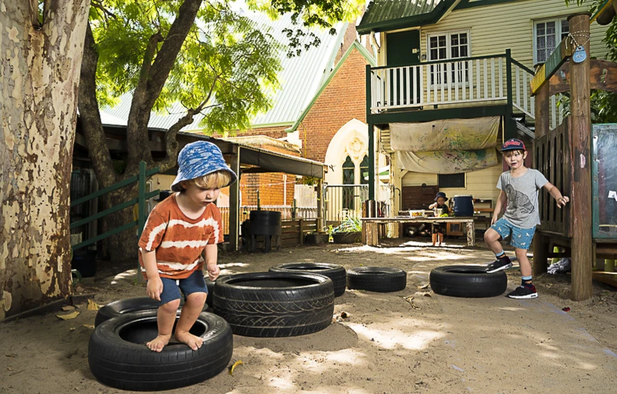 A boy carefully balancing on a large tyre in the outdoor play area