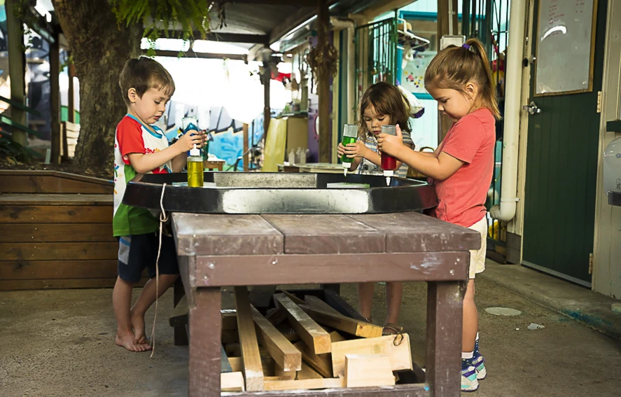 Children playing at the wooden mud kitchen in the yard
